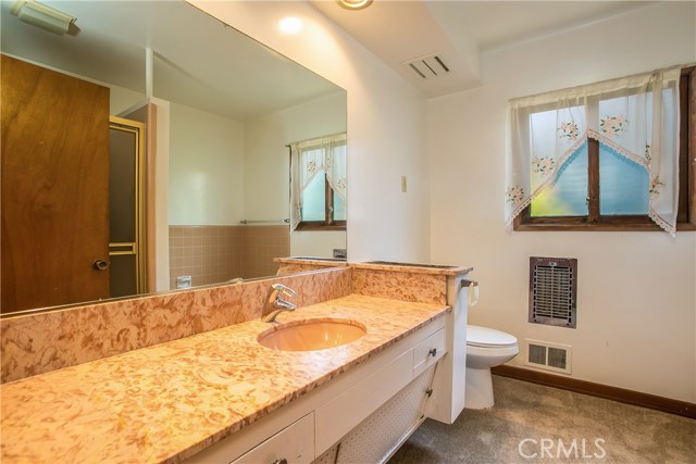 The large bathroom has a bathtub and a separate shower.  There is a large vanity cabinet with a stone countertop.