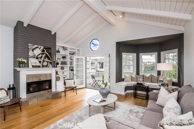 Bright and airy living room with fireplace, balcony, bay window with seating nook.