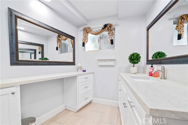 Downstairs bathroom with quartz counter tops, shaker style cabinets and dual sided mirrors.