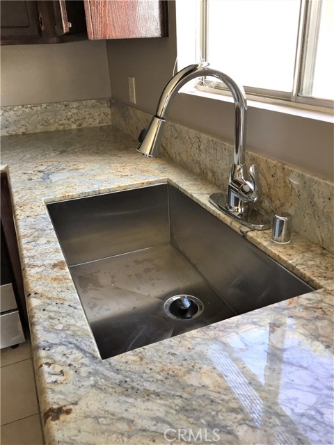 A contemporary single-basin stainless steel sink and faucet with spray arm offer added utility.