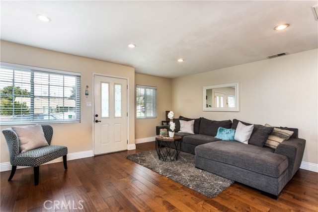 Living room with recessed lights and gleaming hardwood floors.