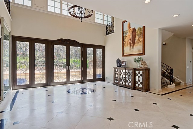 Luminous with clerestory windows and a wall of glass at the entry, the tall ceilings in the Foyer create a lovely entrance, detailed with white stone floors with black inlay.