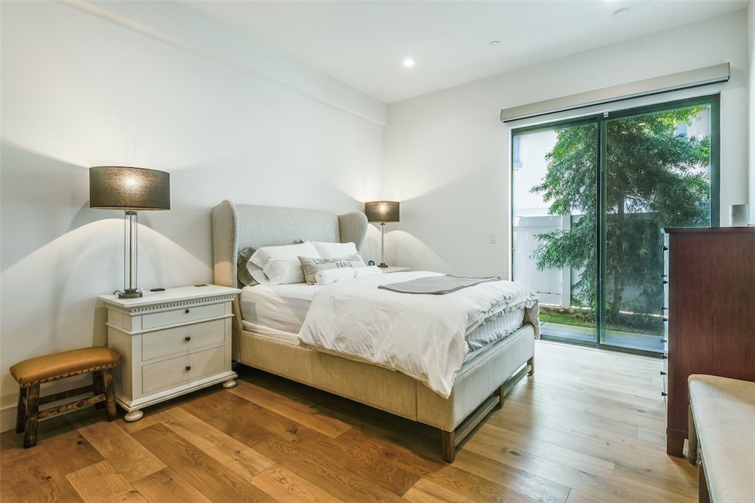 Lower level bedroom featuring wide plank oak flooring, recessed lights, direct access to the side patio