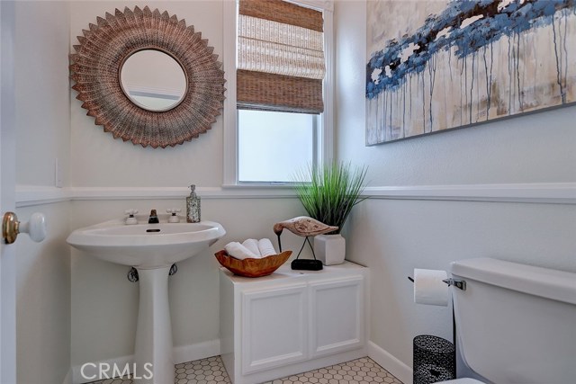 Powder room located on second floor with penny tile flooring and custom window treatment.