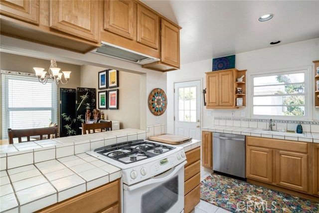 Remodeled kitchen has maple cabinetry, tiled floors and counters, built-in appliances and recessed lighting. Sunny and bright kitchen has sink that faces backyard and patio.