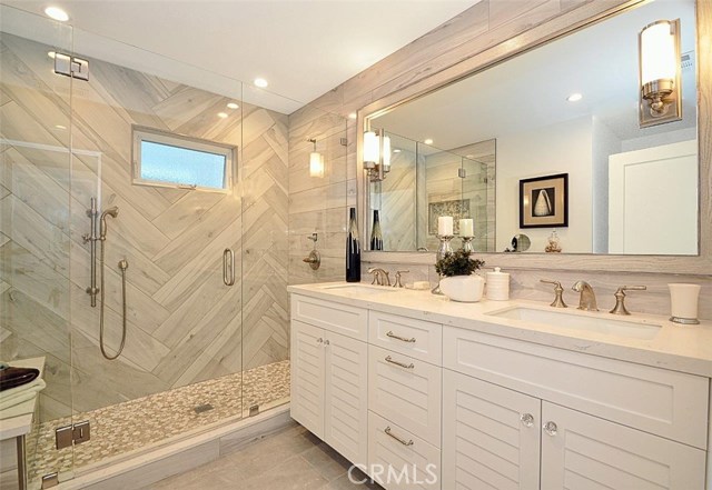 Beautiful herringbone design of tiles in master bathroom and custom built cabinet with double sinks