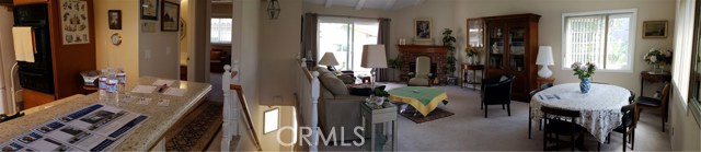 Panoramic view from west wall of the living room showing kitchen bar counter and hallway leading to guest bathroom and master bedroom.