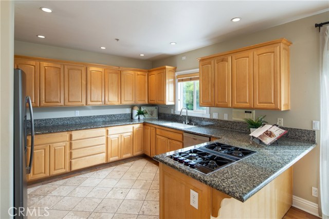 The large kitchen offers granite counters, natural wood cabinetry, newer appliances, and a peninsula with eat-in counter.
