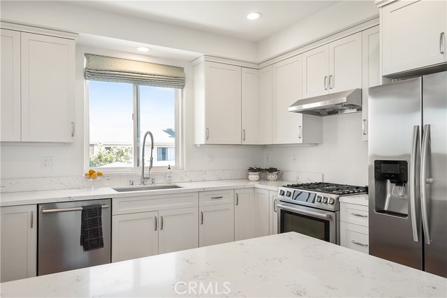 Sunny kitchen with stainless appliances and quartz countertops.