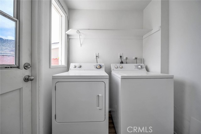 Utility room with washing machine and dryer.  The door leads to a private back yard