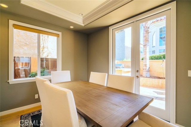 The dining area opens with french doors to the back yard, BBQ area visible to the left of the palm.
