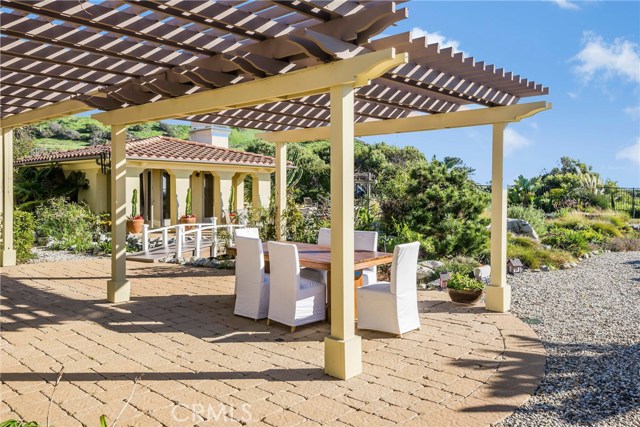 Really nice trellace in year yard with stone pavers and the guest house in background.