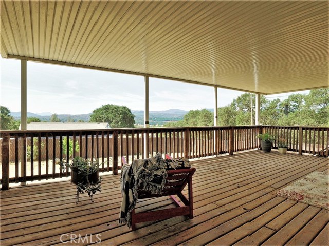 Large covered deck with stairs to the backyard and two sliding glass door entrances to the house: one from the living are, and one from the bonus room.