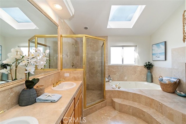 Primary Bathroom with double sinks, walk in shower, luxurious soaking tub and skylight with fireplace to the right