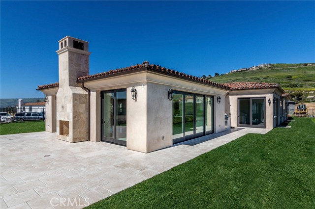 Lush landscaping, outdoor fireplace, and tiled area for entertainment overlooking the pool and view.