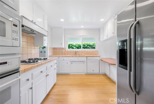 Kitchen with refrigerator, oven, microwave, dishwasher and stove top with exhaust fan.