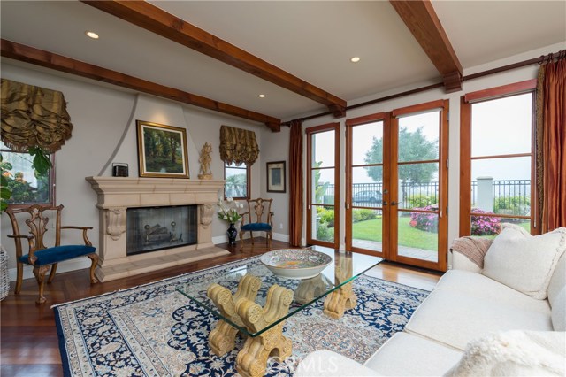 Fabulous formal living room with Mahogany floors, lovely fireplace with mantel, and 8ft French doors that open to the beautifully manicured gated front yard!