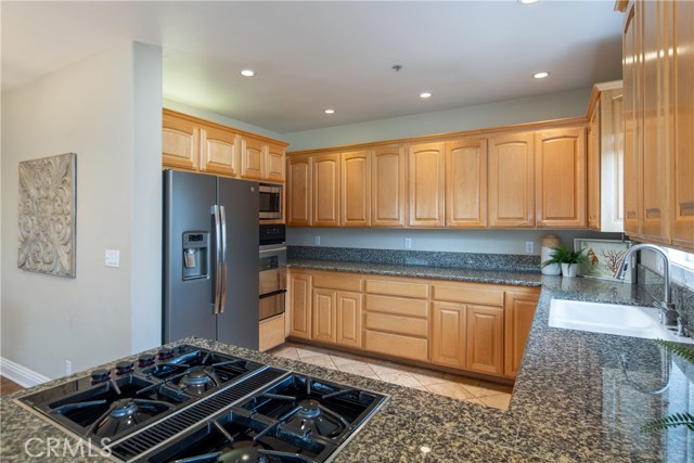 The large kitchen offers granite counters, natural wood cabinetry, newer appliances, and a peninsula with eat-in counter.