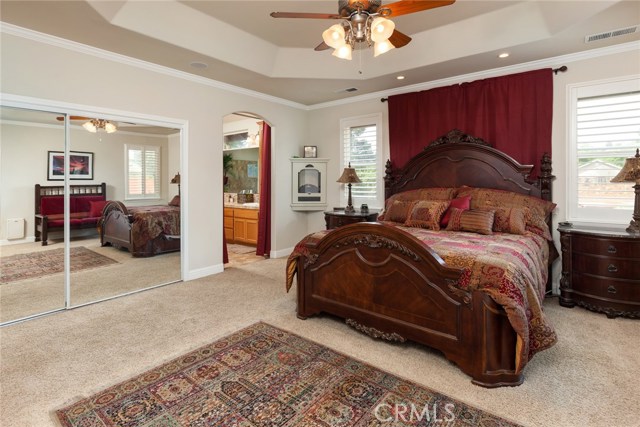 Master bedroom with high ceilings, windows and door out to the backyard patio area.