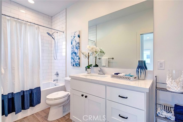 Upstairs back bathroom, en-suite.  Subway tile, porcelain wood-like tile flooring, Calico Quartz countertops.