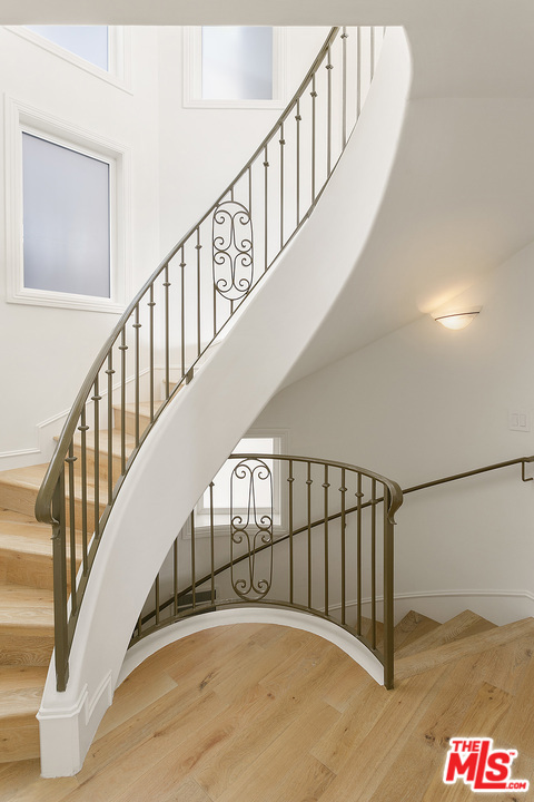 Spiral staircase wi wrought iron railing, wood floors & frosted privacy gla  (nd / main floor).