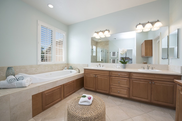 This is a spacious bathroom filled with natural light, a large soaking tub, a shower with ocean view, and a large walk in closet.