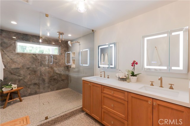 Luxurious spa inspired primary bathroom featuring dual vanities, an oversized walk-in shower with multiple shower heads and refined designer finishes throughout.