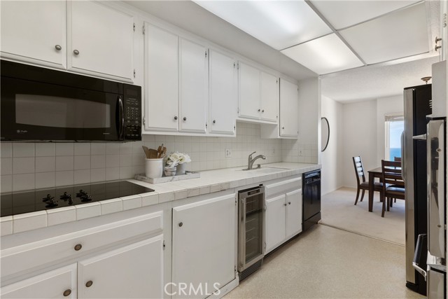 The kitchen is appointed with refrigerator, range, dual-ovens, microwave, dishwasher, wine refrigerator, white cabinetry, ample storage and large panty.