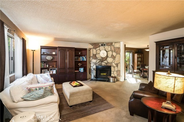 Living room appointed with gas fireplace and large window, letting in morning light.
