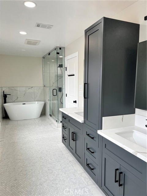 Roomy master bathroom with double vanities, linen cabineta and luxe mirrorred medicine cabinets