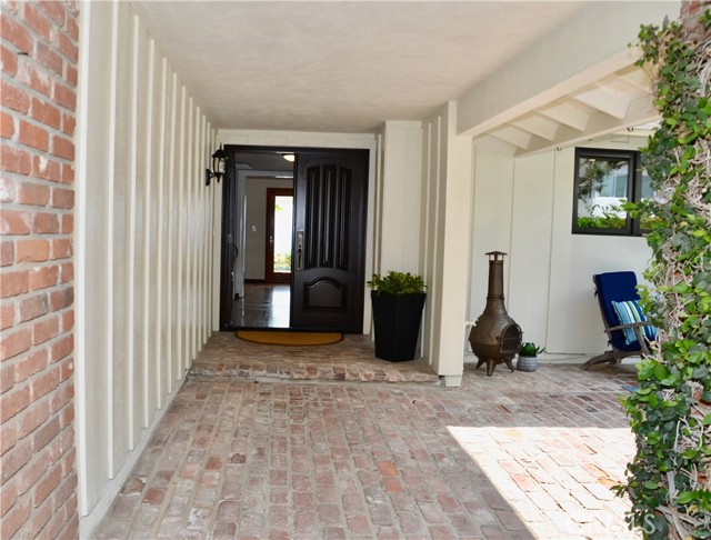 Closer view of the double wood front door and  spacious brick patio which is fully enclosed and offers a sunny alternative for enjoying the outdoors.