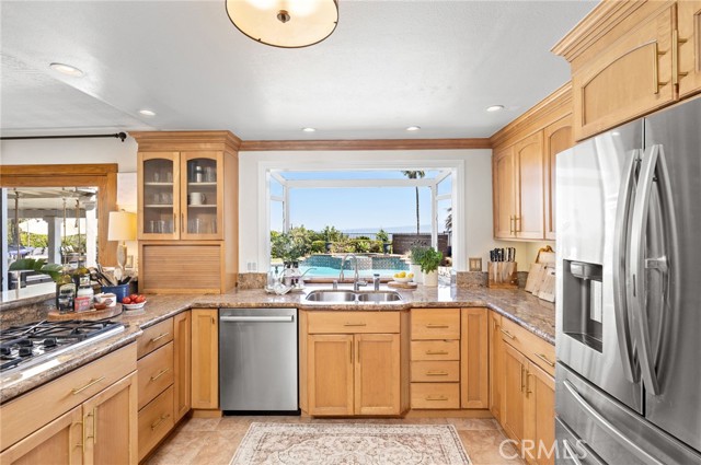 Bright eat-in kitchen, featuring stainless steel appliances and custom cabinets, flows seamlessly into the formal dining room and  family room.