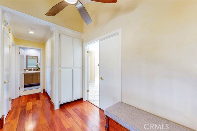 Upstairs hallway with ample storage closets, wood flooring and ceiling fan