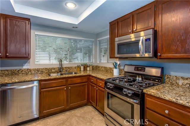 Renovated kitchen features granite countertops and backsplash, wood cabinetry, stainless appliances and ceramic tile floors.