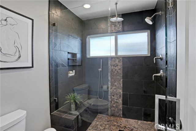Primary Shower has Multiple Shower Heads and A convenient resting seat inside the shower enclosure.
