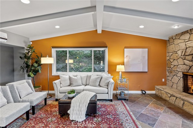 The family room area of the great room with vaulted open beamed ceilings, warm PV Stone fireplace, slate floors, recessed lighting.