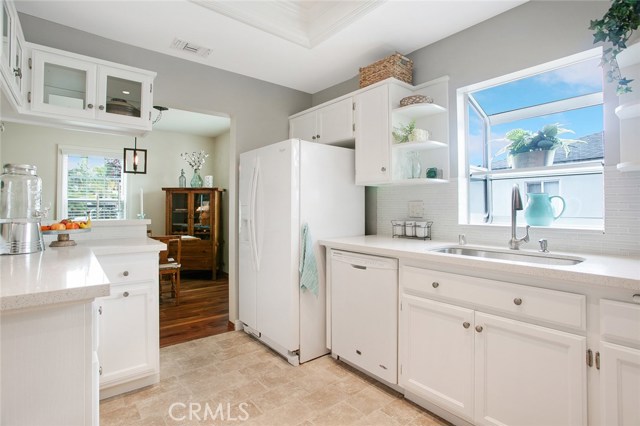 Upgraded Kitchen boasting of pristine white cabinets, quartz counter tops, a backsplash wall of glass mosaic tiles, an elegant ceiling with recessed lights, furnished with Refrigerator, Dishwasher and Gas Range & Stove.