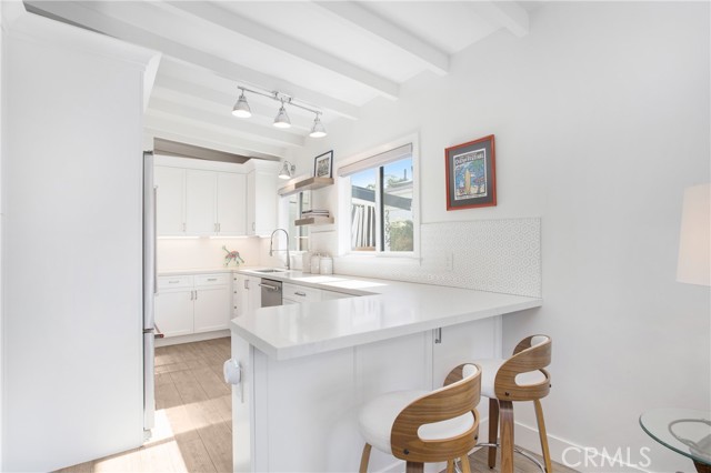 Breakfast bar, quartz counters, bright white kitchen with ample storage.