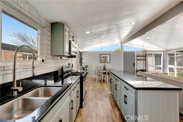 Remodeled kitchen with cabinets, subway tile, granite kitchen island, and stainless steel appliances