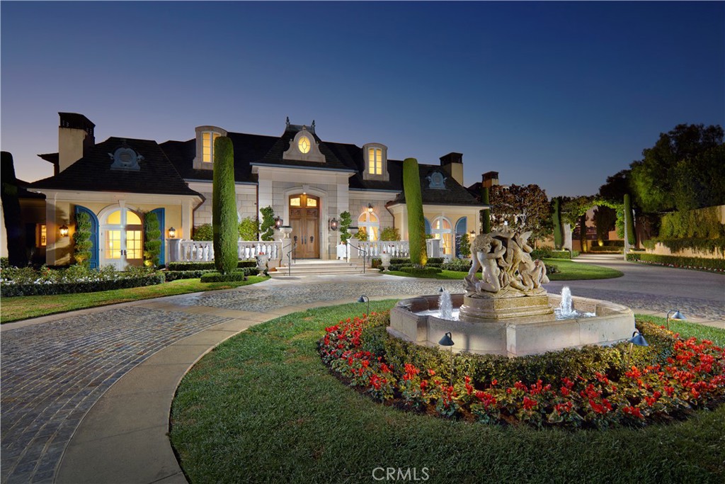 Representing the ultimate union of ocean-view living, timeless architecture, and extravagant luxury, this custom estate in Laguna Niguel’s guard-gated Bear Brand Ranch is without compare. Crafted in the style of opulent French chateaus, the grand residence occupies a sprawling homesite of nearly 1.4 acres, capturing panoramic views of the Pacific Ocean, Catalina Island, coastline, sunsets, and city lights from its prime location at the end of a cul-de-sac featuring just five other estates. Custom entry gates open to a long driveway lined with Italian cypress trees, leading to a circular motor court. The residence boasts four ensuite bedrooms and five-and-one-half baths across approximately 7,948 square feet. An appropriately magnificent double-height foyer introduces the bright and lavish interior, showcasing a circular staircase. To the left, a library with wood-paneled walls and ceiling awaits, while an ocean-view living room beckons guests beyond a grand hall. A walk-in wet bar with walls of windows serves the living room and an impressive family room, which features a towering open-truss ceiling and a handsome stone fireplace. Chefs of all skill levels will feel at home in the dual-island kitchen, appointed with marble countertops, custom cabinets, Wolf appliances, and a built-in refrigerator. The kitchen leads to a butler’s pantry with a separate walk-in pantry, as well as a casual dining and sitting room accented by stone walls.
Three bedrooms are located on the first level, including a junior suite with separate outdoor access. Ocean views continue on the second level, which is reserved for a gym, studio, and a top-tier primary suite. A covered view terrace, multiple sitting areas, a fully appointed bath, and two walk-in closets enhance the primary suite. Additional features include beamed ceilings, an elevator, stone and hardwood flooring, impeccable millwork, and a four-car garage. Formal gardens complement a gorgeous, park-like backyard with a resort-style pool and spa, event lawn, heated patios, and a built-in BBQ bar.