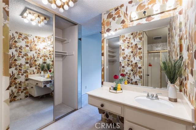 primary vanity with two closets and wardrobe mirror doors