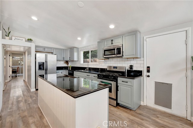 Remodeled modern kitchen with ample cabinets, subway tile, a kitchen island, and stainless steel appliances