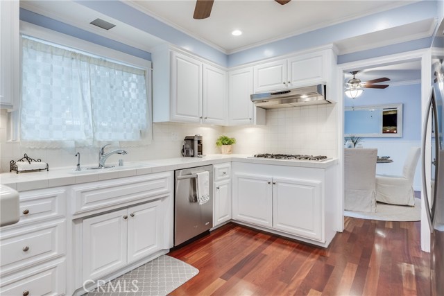 Kitchen with a coastal inspiration offers breakfast bar, white shaker cabinets, stainless appliances and hardwood floors