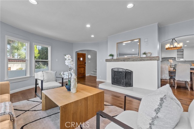 The living room is appointed with rich hardwood floors, an elegant stone fireplace, and subtle designer tones.