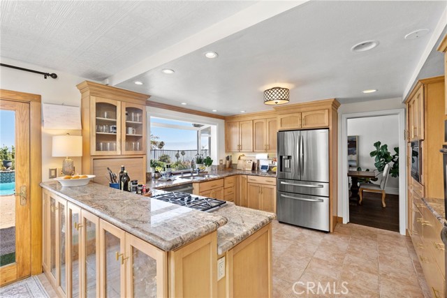 Bright eat-in kitchen, featuring stainless steel appliances and custom cabinets, flows seamlessly into the formal dining room and  family room.