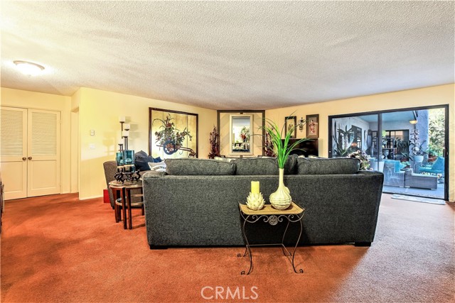 This View of the Living Room shows the Large Adjoining Deck to the right and the Entry on the left to the Long Hallway with a Storage Closet leading to the 2 Bedrooms and 2 Full Bathrooms.