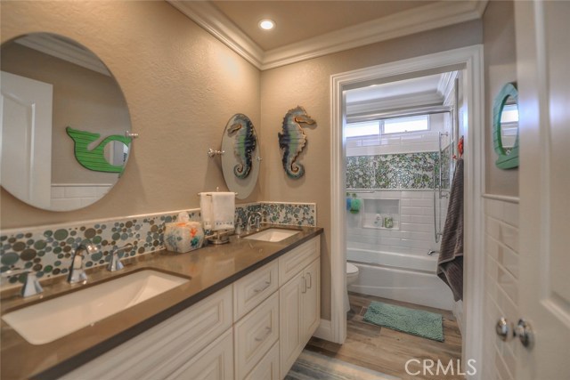 Upstairs hall bath with quartz counters, fun bubble glass tile accents, dual sinks, tile flooring, and a laundry chute!