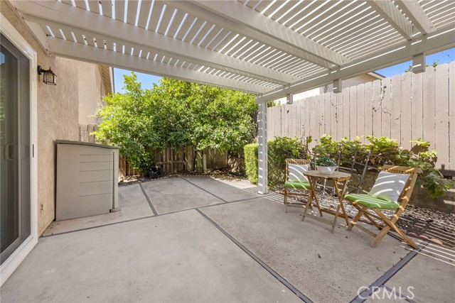 Backyard with a spacious concrete patio and a covered area for shade and outdoor enjoyment.