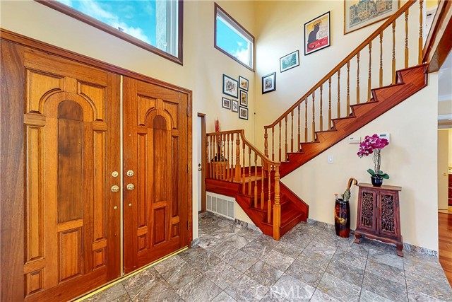 Double door entry with cathedral ceiling next to wooden stairs