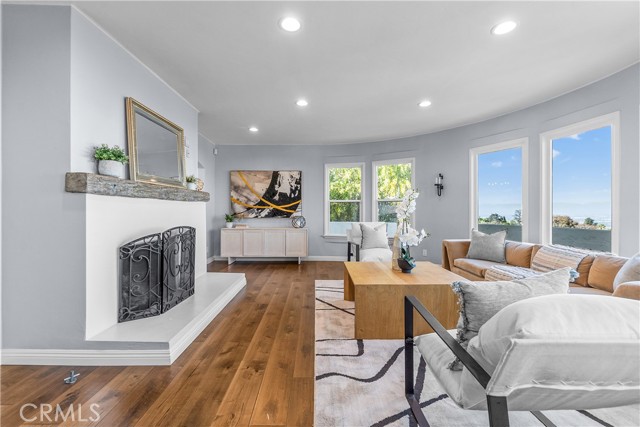 The living room is appointed with rich hardwood floors, an elegant stone fireplace, and subtle designer tones.